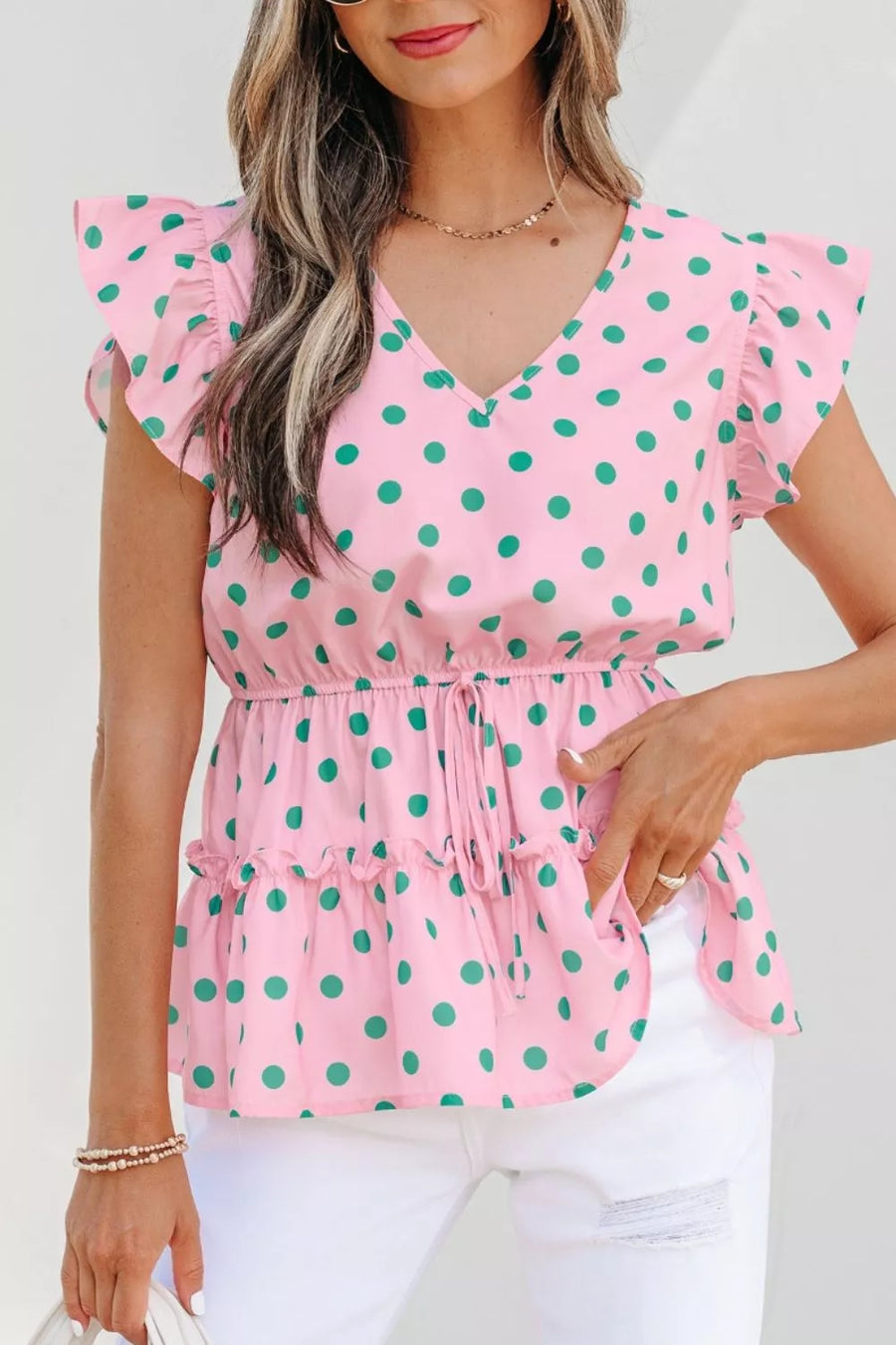 Pink polka dot blouse with ruffled sleeves and hem, V-neck, and drawstring waist.