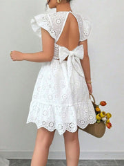 White eyelet mini dress with ruffle sleeves, backless design, and large bow detail.