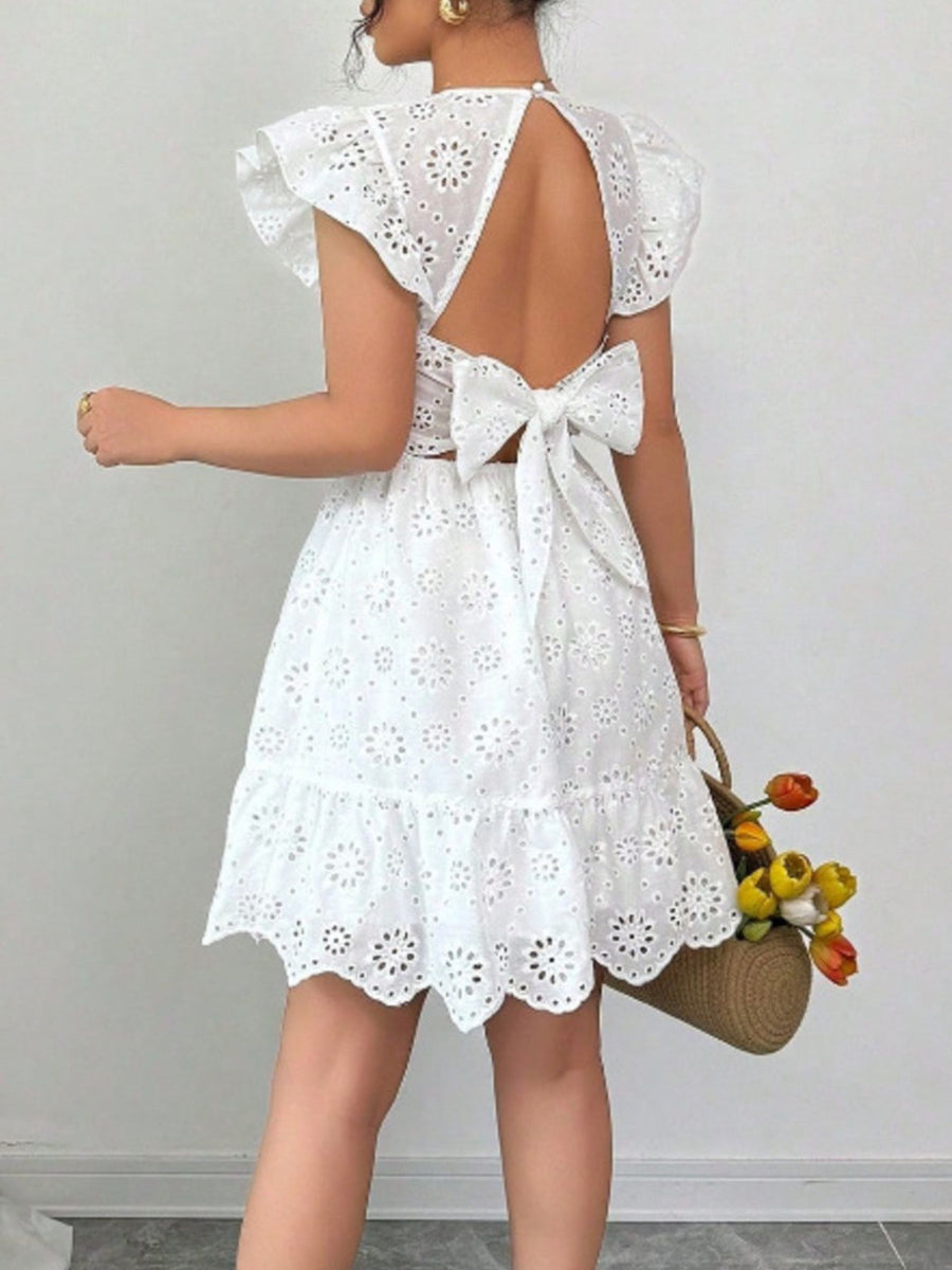 White eyelet mini dress with ruffle sleeves, backless design, and large bow detail.