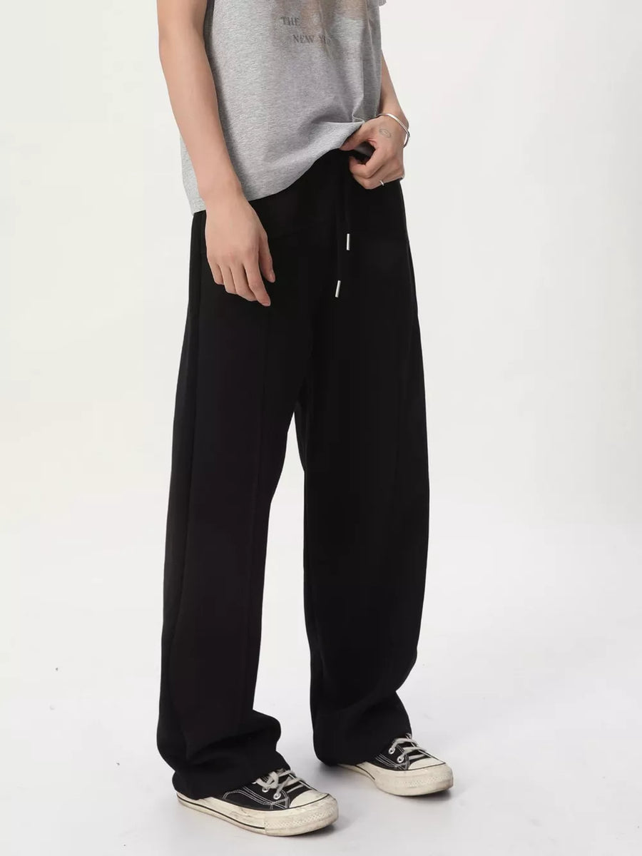 Men's black cotton wide-leg drawstring sweatpants with stitched seams.