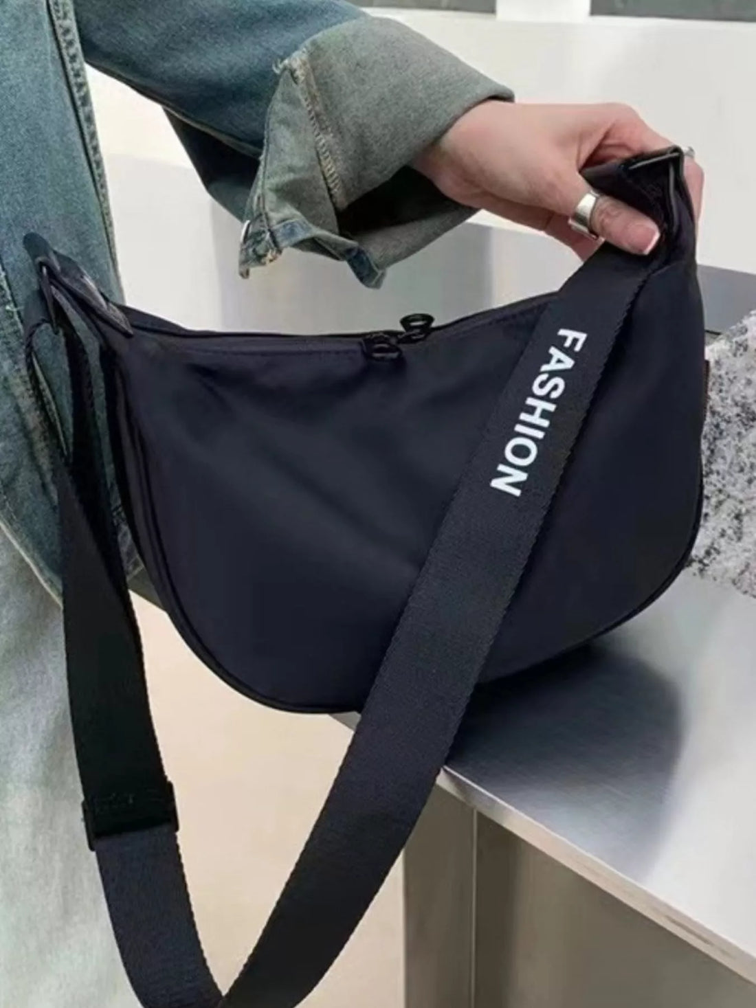 Black crossbody bag with adjustable strap and "Fashion" text detail