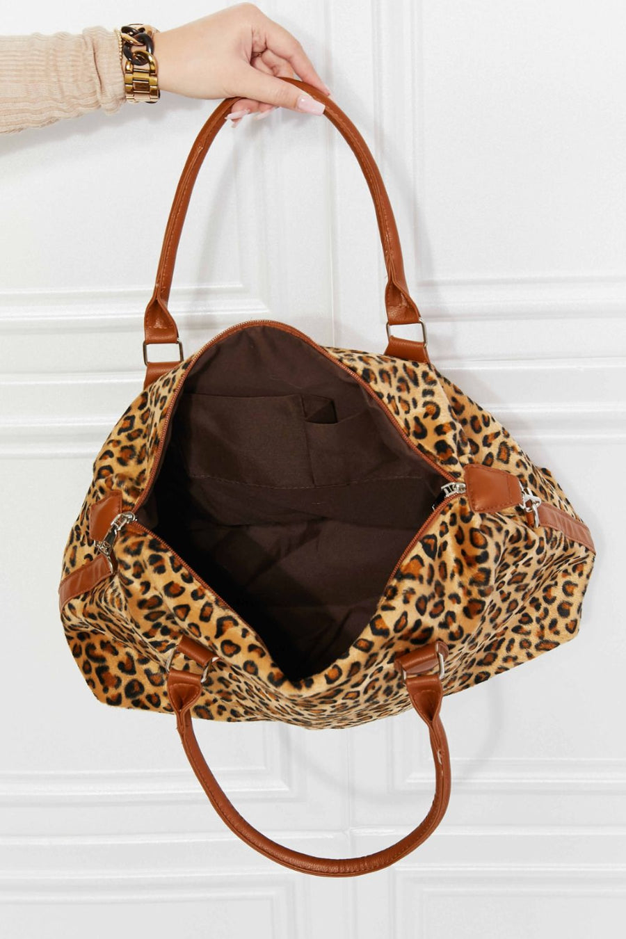 Leopard print travel satchel with brown leatherette trim and handles, open view showing interior pockets.
