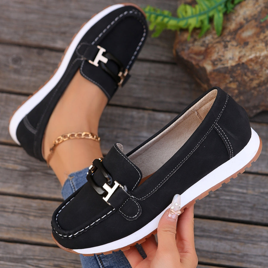 Black slip-on loafers with buckle detail and contrast stitching.