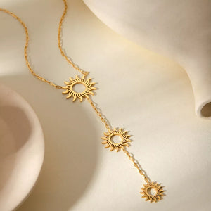 Gold necklace featuring pendant and sun motif