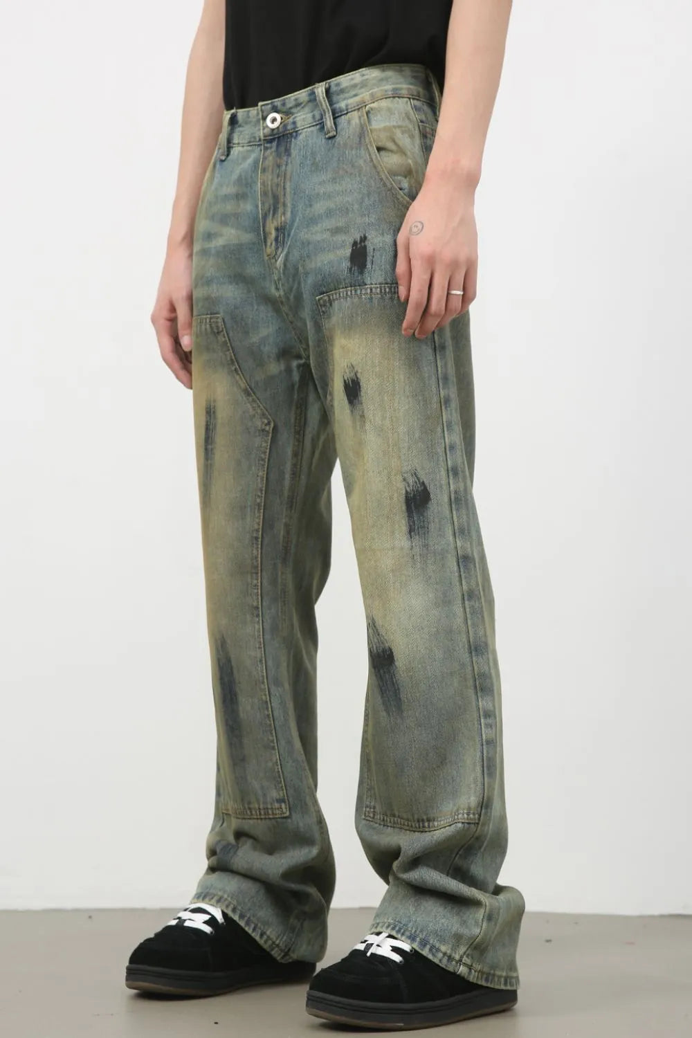 Distressed carpenter jeans in medium wash denim with black paint-like marks and a relaxed fit.