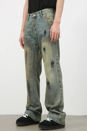 Distressed carpenter jeans in medium wash denim with black paint-like marks and a relaxed fit.