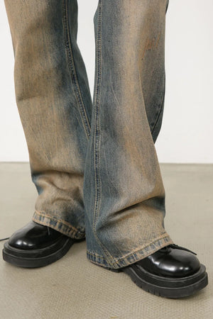 Faded wash bootcut denim trousers in medium, styled with black platform shoes.