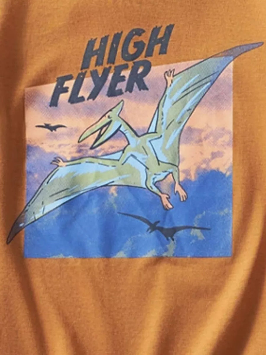 Orange t-shirt with a graphic print of a green pterodactyl flying in a blue sky with clouds and text that says HIGH FLYER.