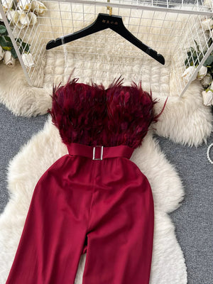 Wine red strapless wide-leg jumpsuit with feather trim bodice and belted waist