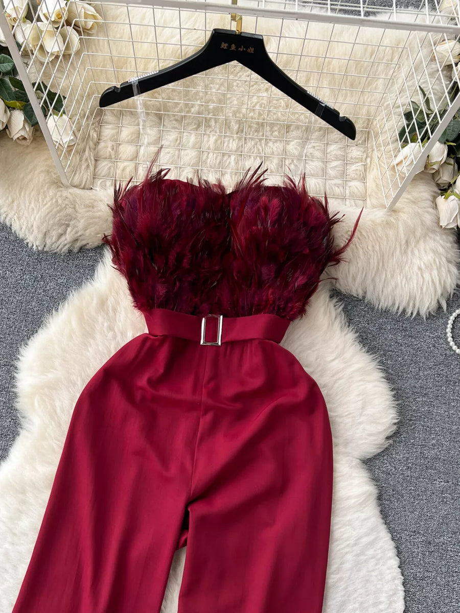 Wine red strapless wide-leg jumpsuit with feather trim bodice and belted waist