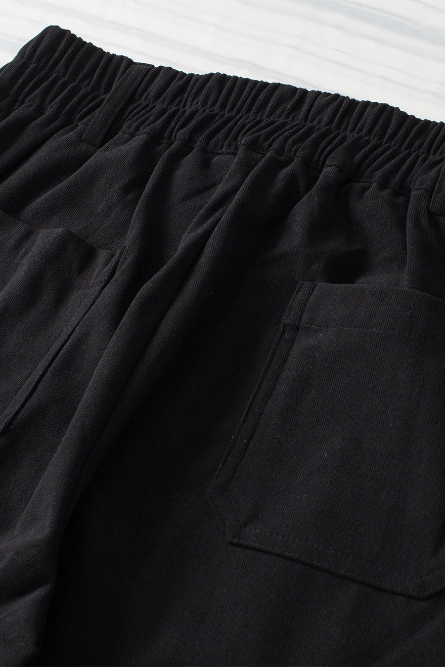 Black seamed front wide leg trousers with elastic waistband and patch pockets.