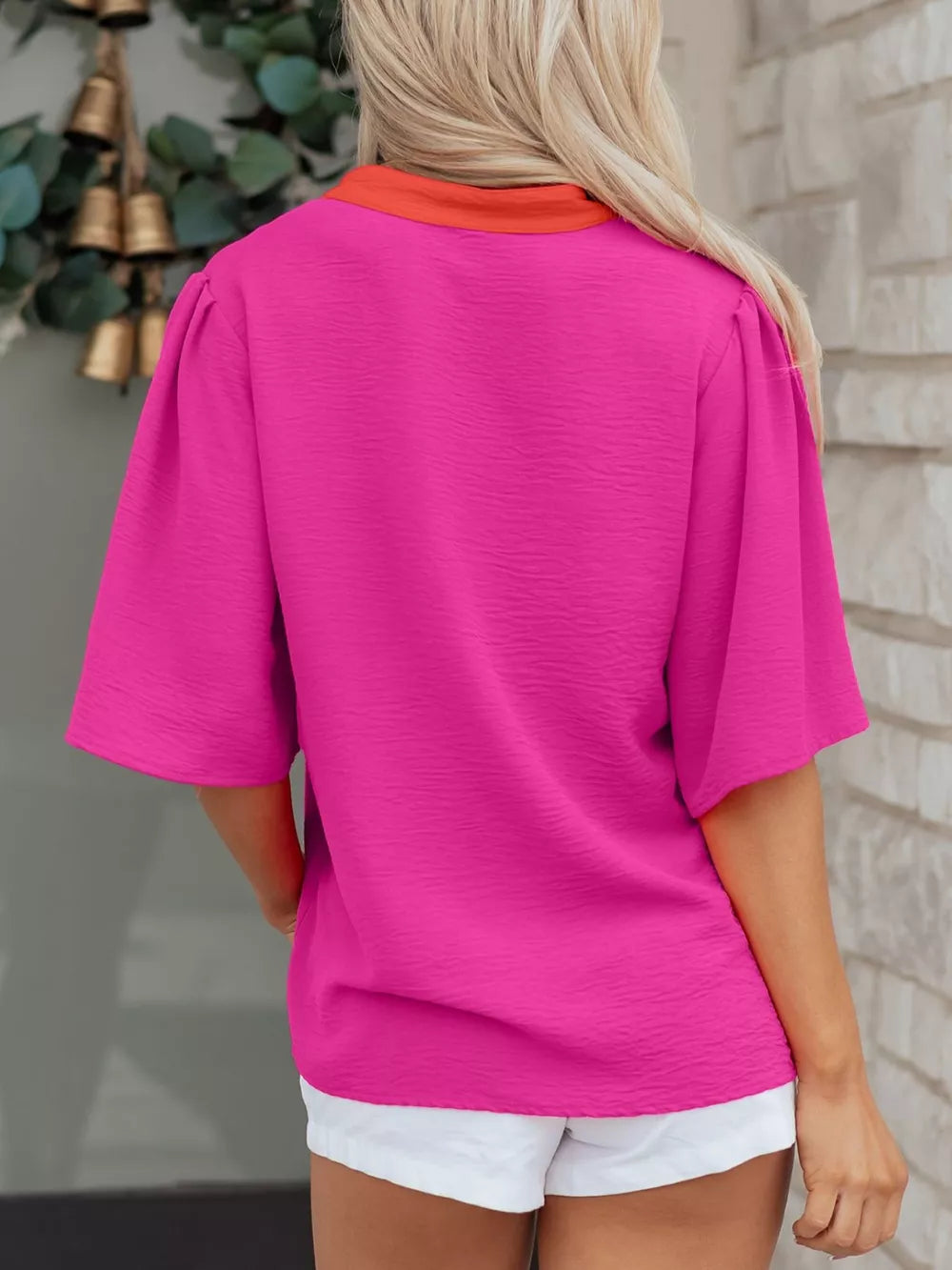 Textured pink V-neck blouse with half sleeves and orange collar detail.