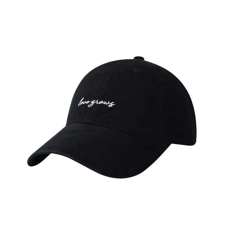 Black cotton baseball cap with embroidered "love grows" text detail.
