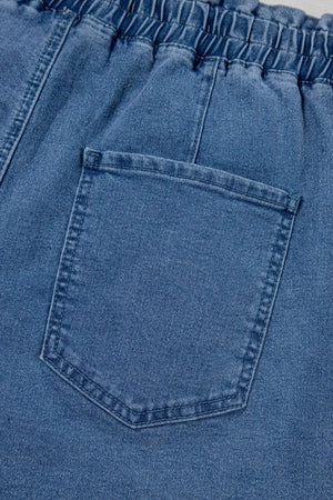 Medium wash denim shorts with paperbag waist and relaxed fit, showing back pocket detail.