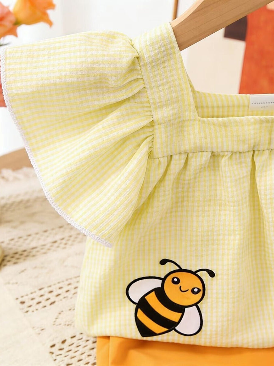 Yellow gingham baby top with flutter sleeves and bee embroidery, paired with orange shorts.