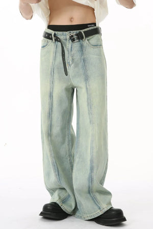 Light wash denim palazzo trousers with vertical seams and a black belt.