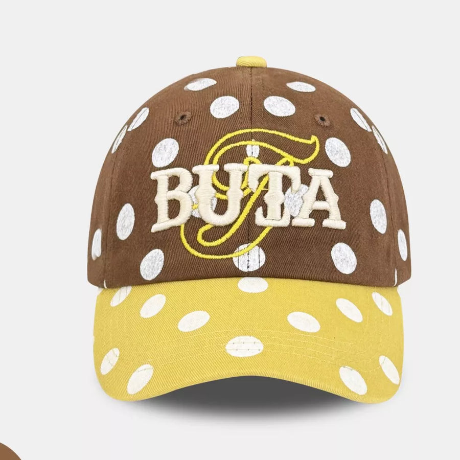Brown polka dot baseball cap with yellow brim and embroidered logo.