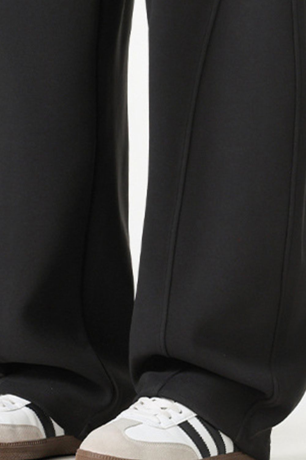 Black relaxed wide-leg sweatpants with drawstring detail and athletic shoes.