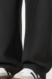 Black relaxed wide-leg sweatpants with drawstring detail and athletic shoes.