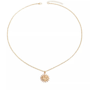 Gold sunburst pendant necklace with a celestial face detail on a delicate chain.
