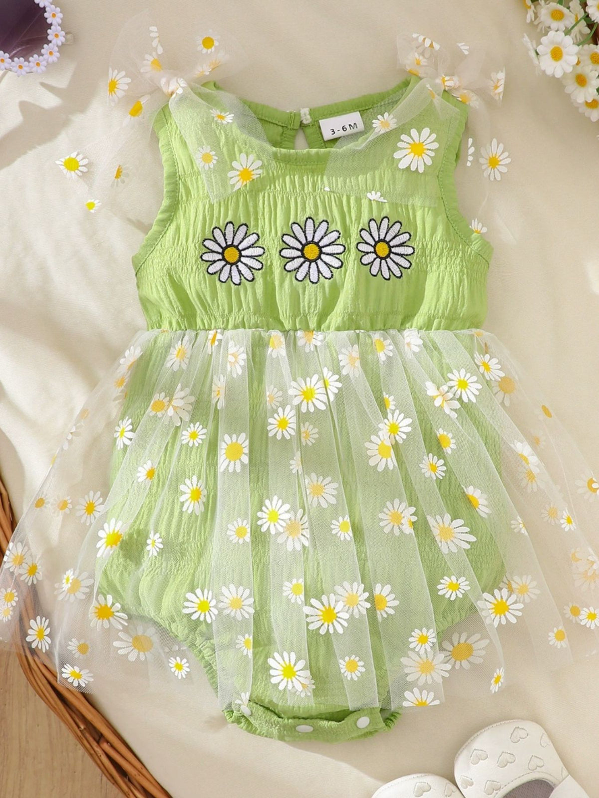 Green daisy embroidered baby bodysuit dress with sheer daisy overlay and bow straps.