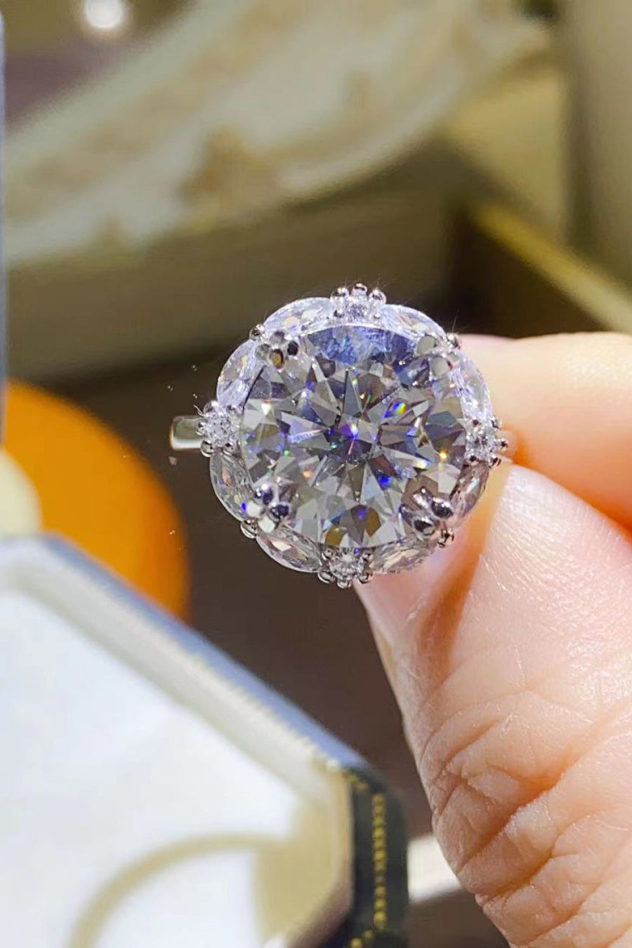 Silver moissanite statement ring with a large round center stone and halo detail.