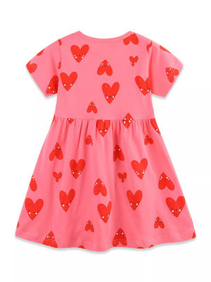 Pink cotton baby dress with playful red heart print, short sleeves, and gathered waist.