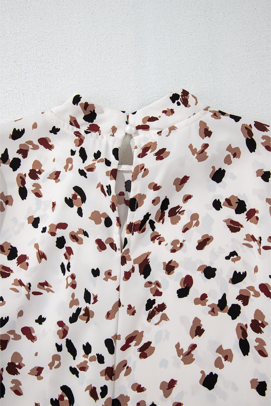 White high-neck blouse with abstract print and button-back detail