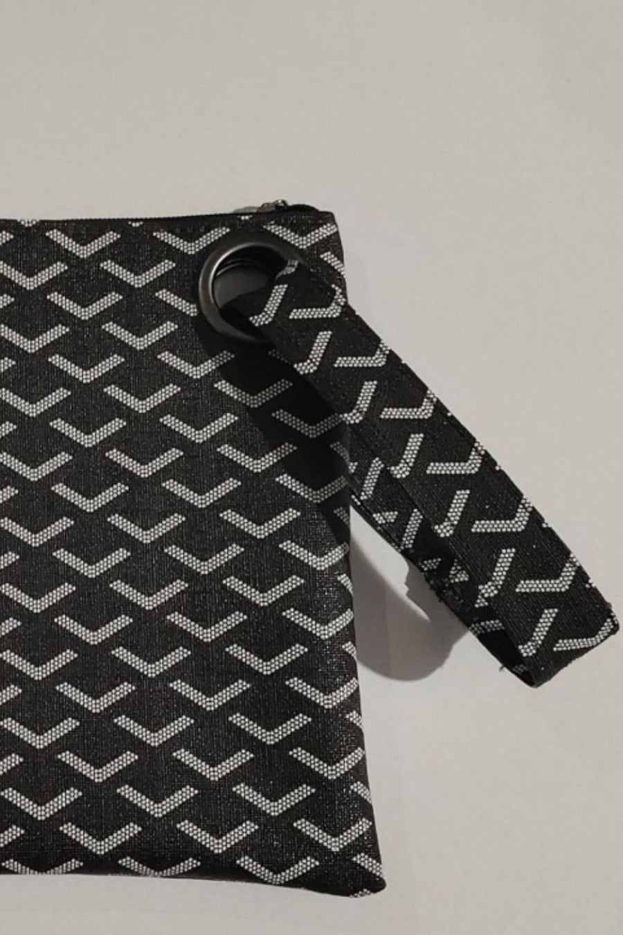 Black clutch bag with white geometric pattern and grommet wristlet detail