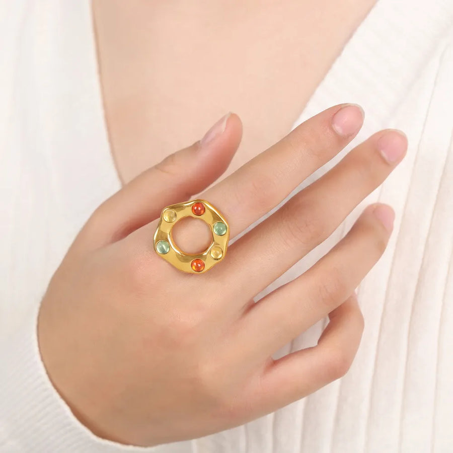 Gold statement ring with colorful gemstones in a halo design.
