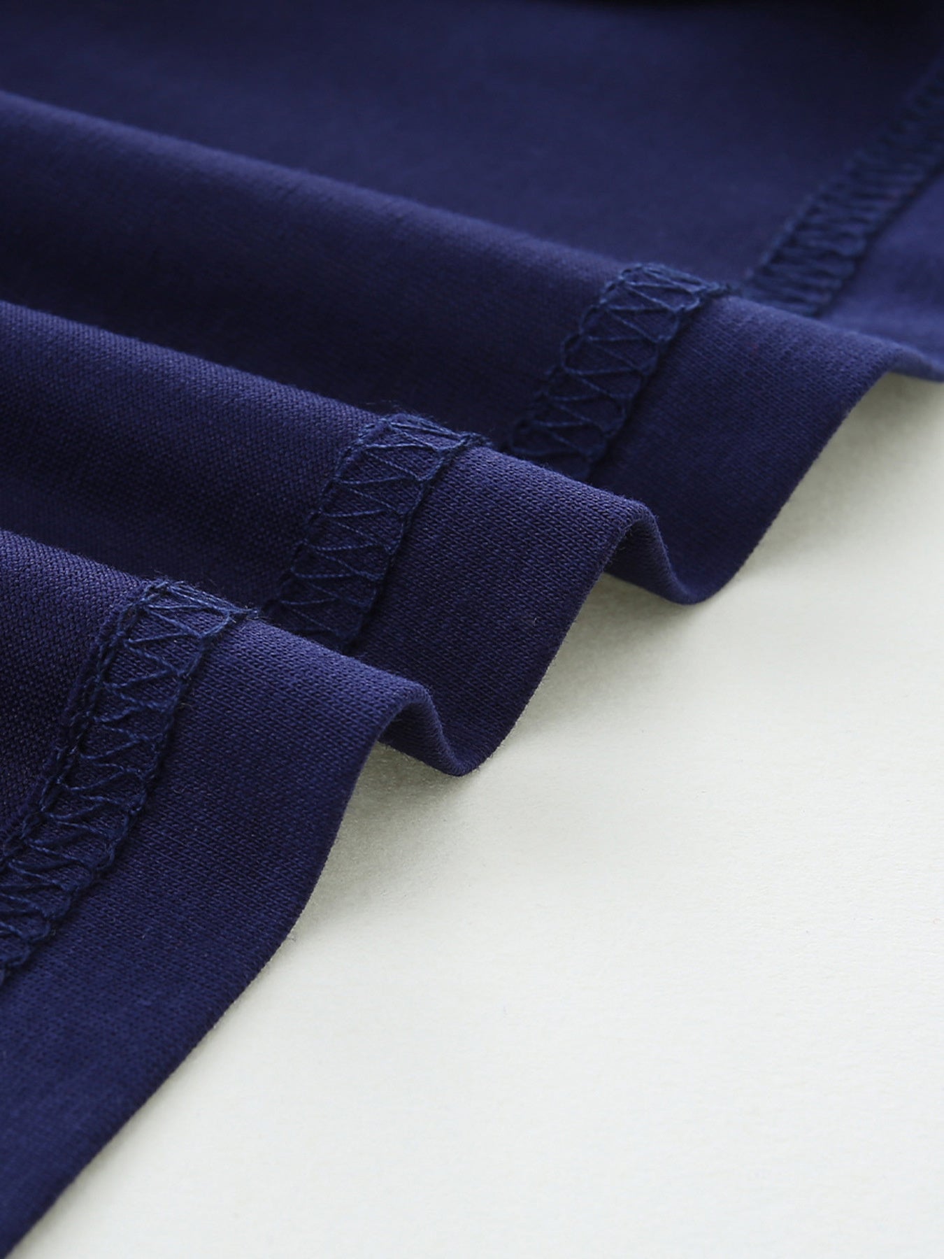 Navy blue cotton t-shirt detail showing reinforced stitching on hem and sleeves.