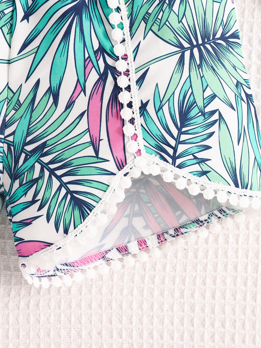 Baby floral shorts with white pom-pom trim and tropical leaf print.