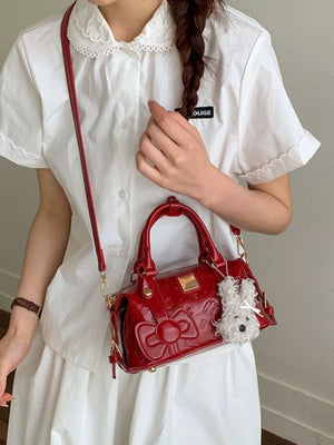 Charming Mini Bow-embellished Crossbody Bag in shiny red with a fluffy white charm.