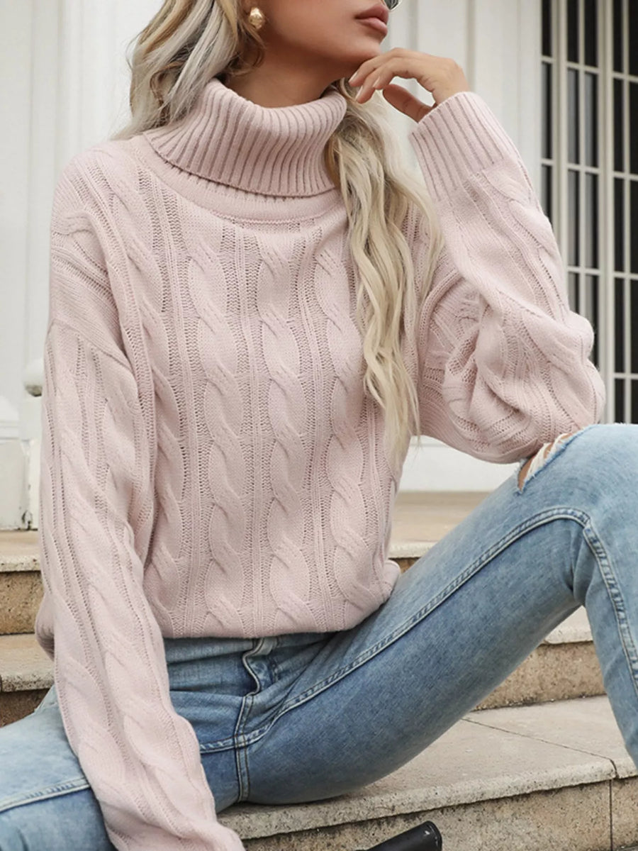 Pink cable knit turtleneck sweater with ribbed collar and cuffs.