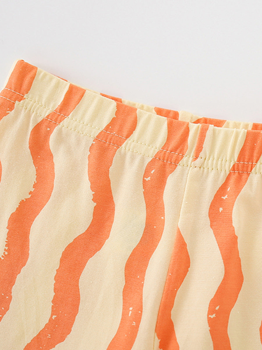 Toddler shorts with elastic waistband and wavy orange stripes on cream cotton fabric.