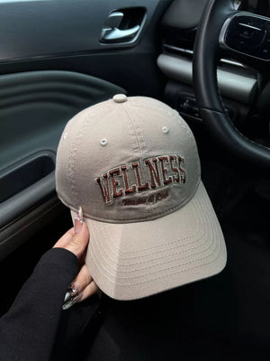 Khaki cotton baseball cap with embroidered "WELLNESS" text