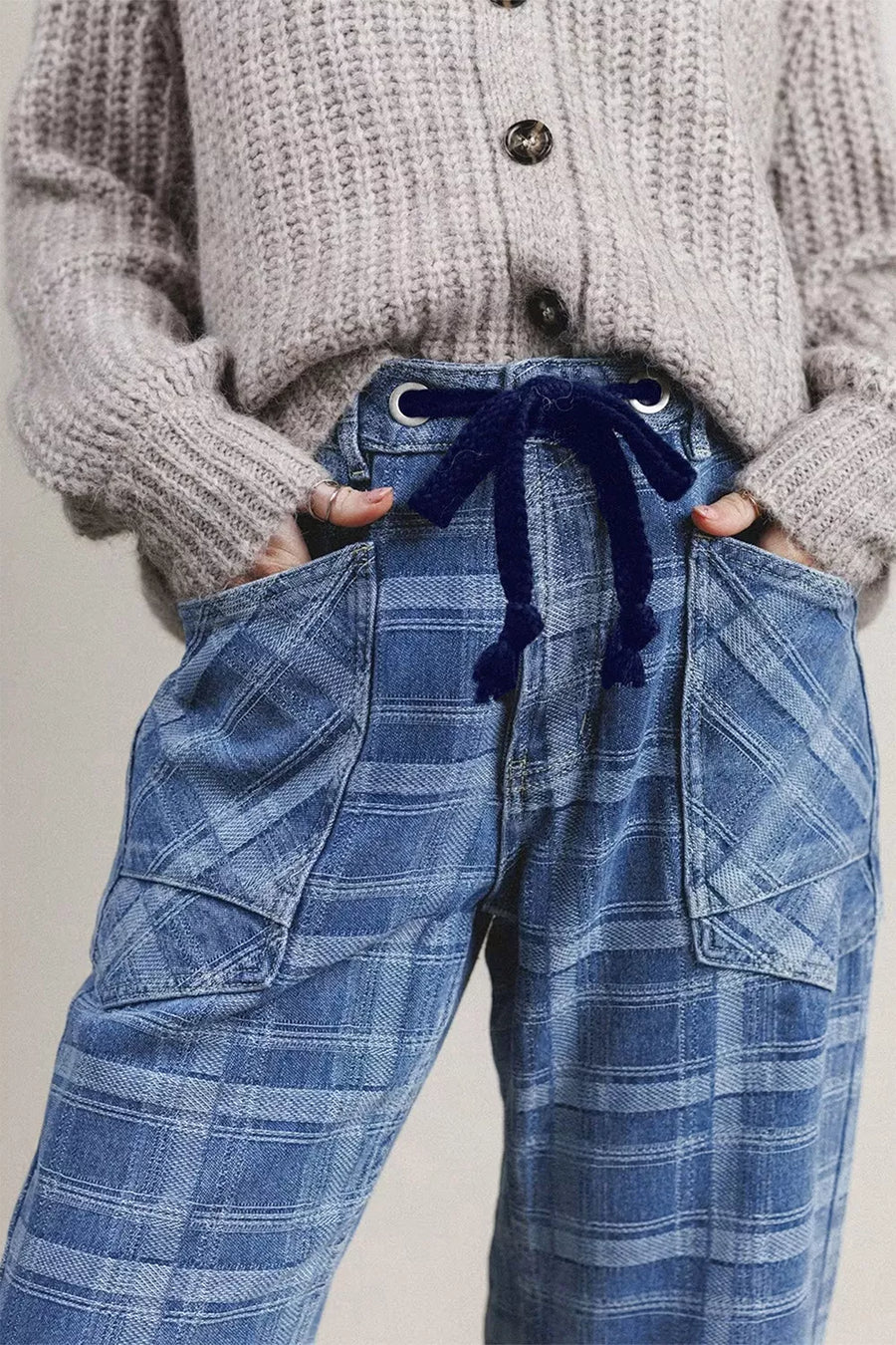 Plaid denim jeans with drawstring waist and grommet details.