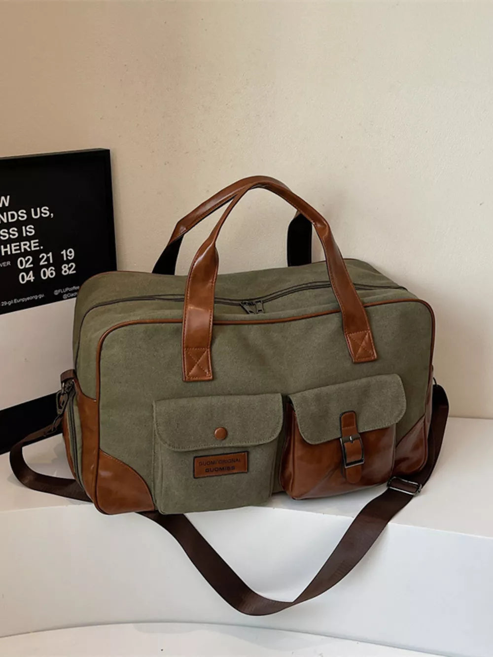 Sophisticated green canvas travel bag with brown leather accents and multiple pockets.