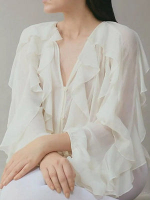 White sheer long-sleeve blouse with cascading ruffles and a deep V-neckline.