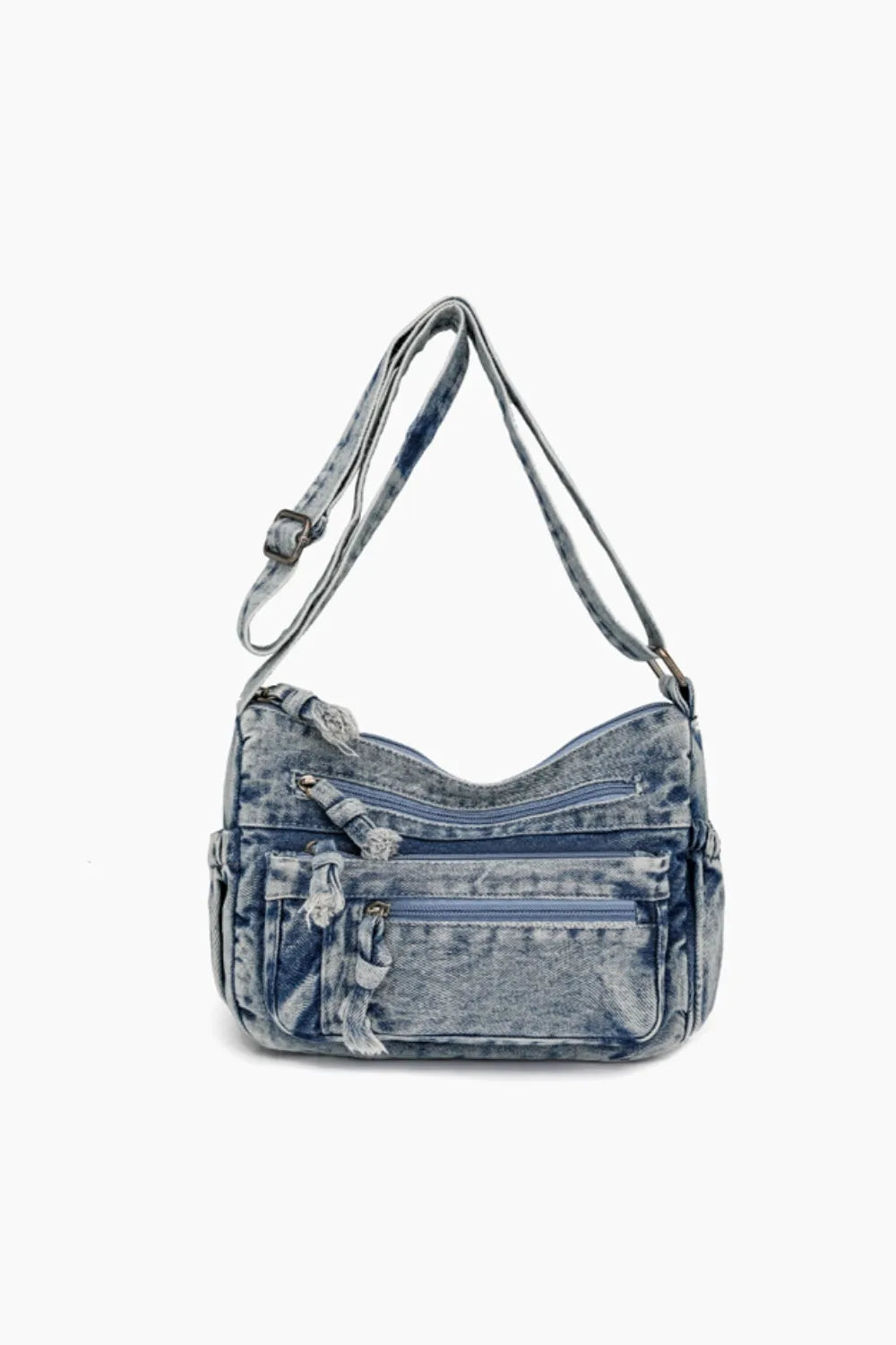 Acid wash denim crossbody bag with multiple zippered pockets and tassel details.