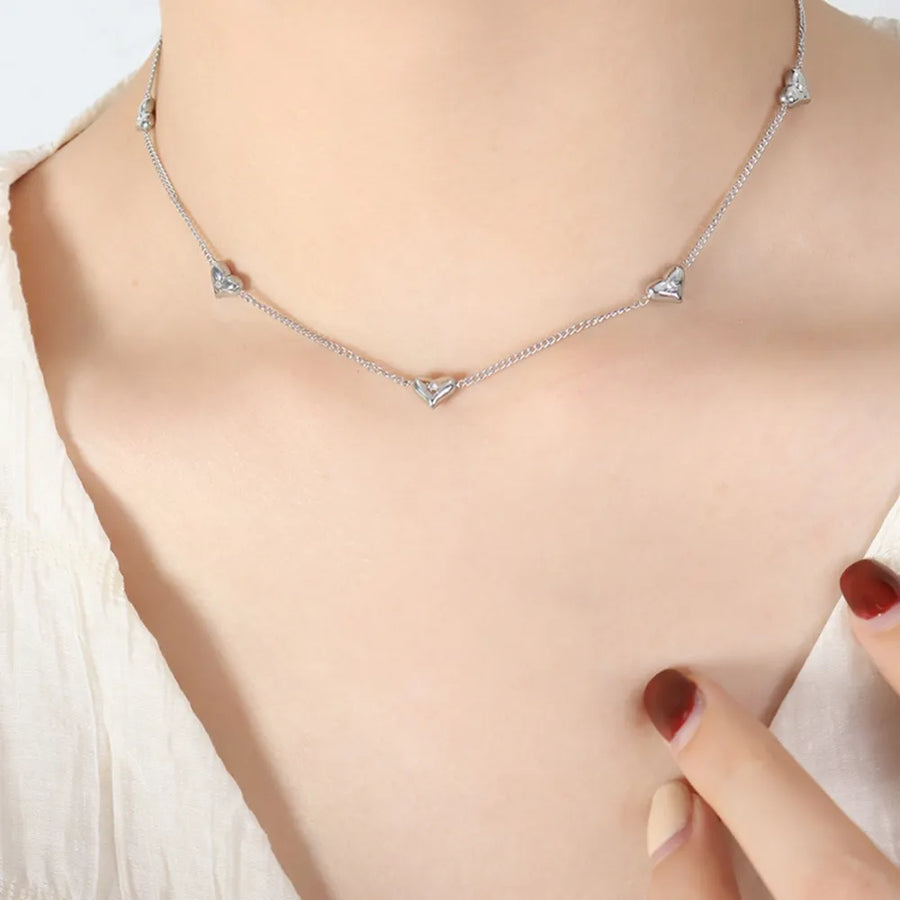 Silver chain necklace with small heart-shaped zirconia charms.
