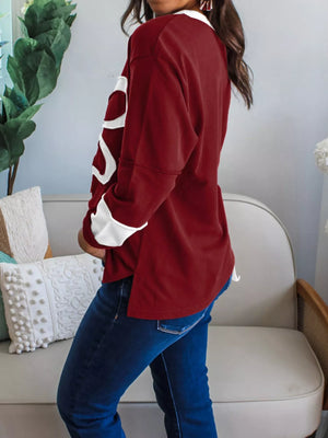 Burgundy long-sleeve top with white flower patches and a high-low hem.
