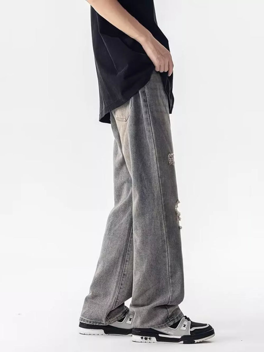 Men's loose fit grey distressed jeans with ripped details.