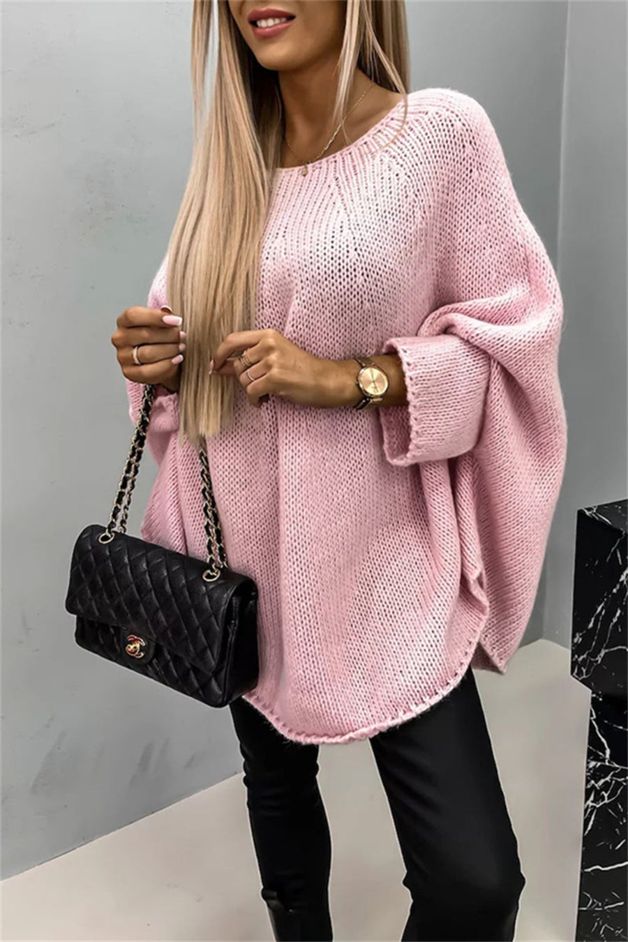 Relaxed blush pink knit sweater with cape sleeves and a round neckline.