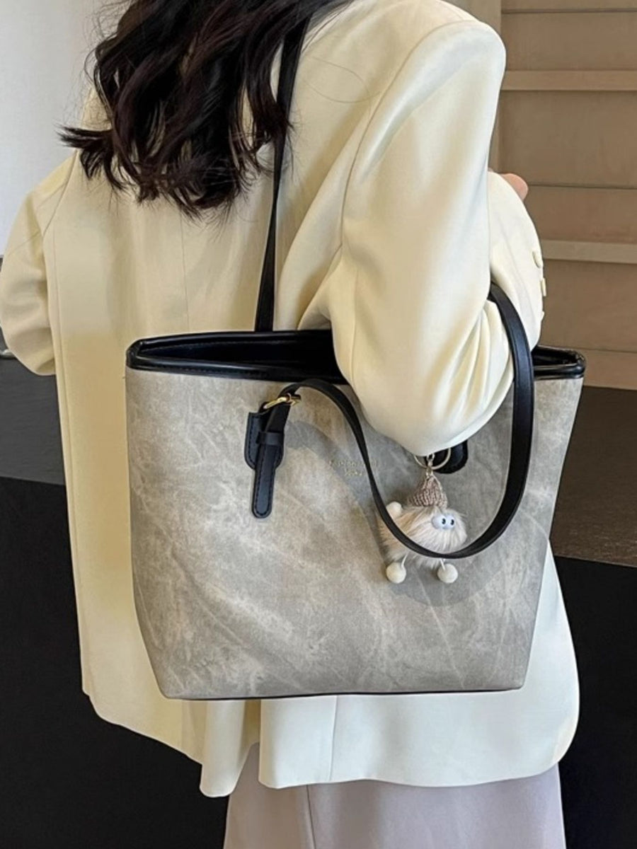 Distressed pu leather tote bag in dark gray with a fuzzy charm and buckle accents.