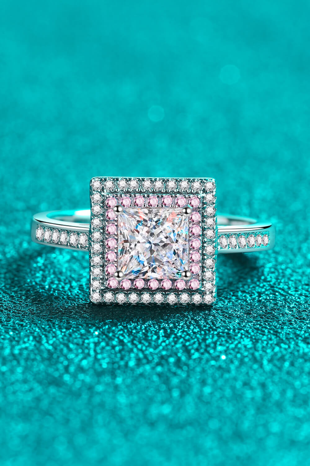 Princess cut halo ring in silver with pink accents and a central square diamond.