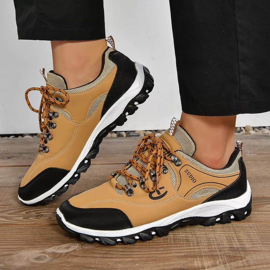 Brown low-top sneakers with patterned laces and black accents.