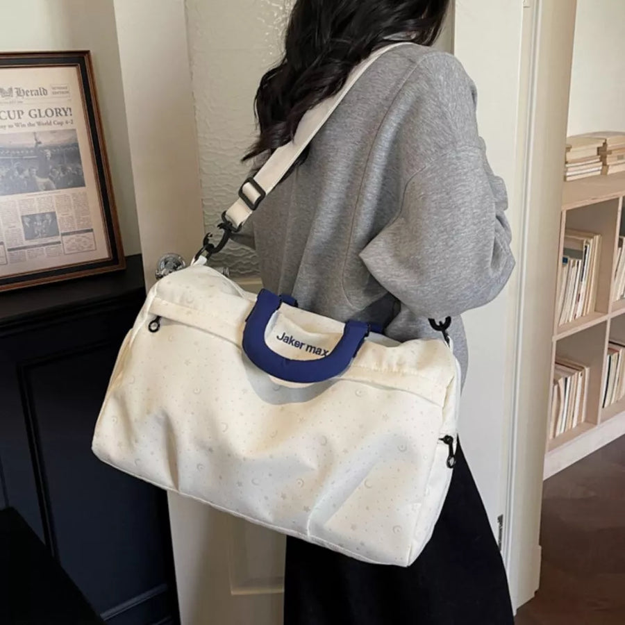 Cream white duffel bag with star and moon pattern, blue handles, and adjustable strap.