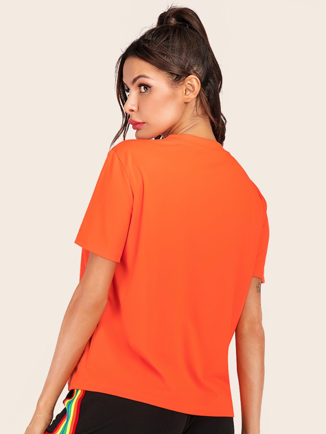Orange basic t-shirt with short sleeves and a crew neck, styled with rainbow stripe pants.