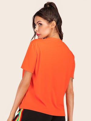 Orange basic t-shirt with short sleeves and a crew neck, styled with rainbow stripe pants.